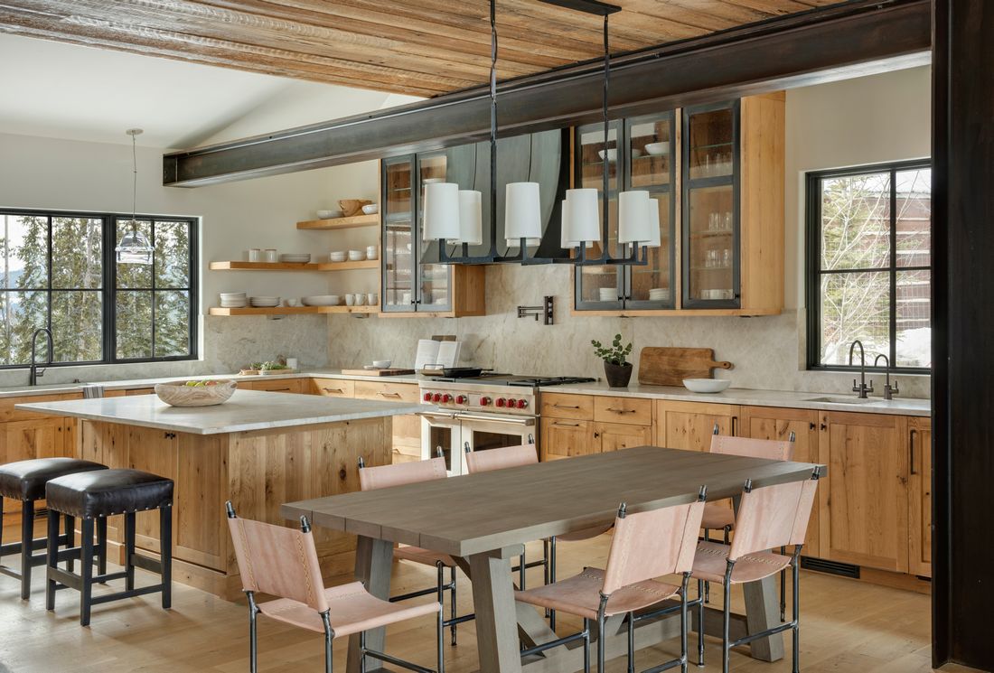 A kitchen with wooden cabinets , a table and chairs.