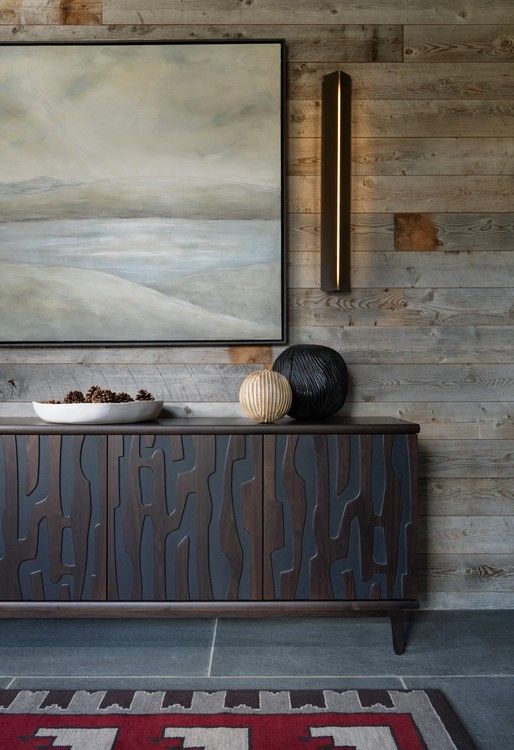 A wooden cabinet with a painting on the wall above it.