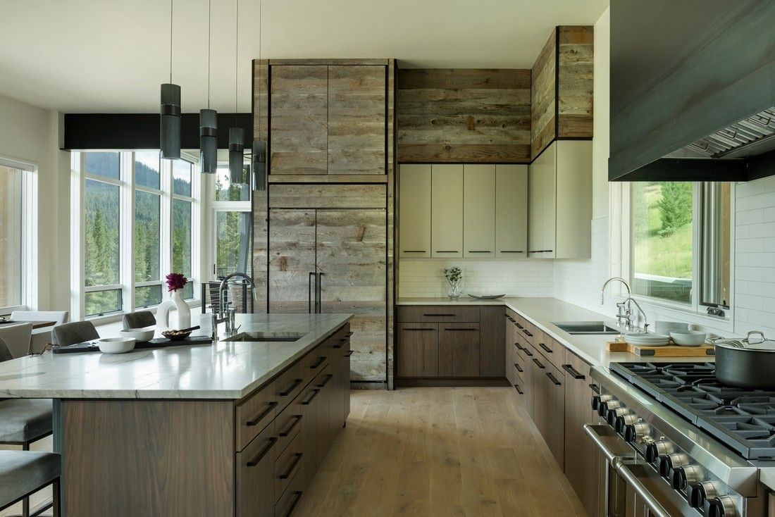 A kitchen with wooden cabinets , stainless steel appliances and a large island.