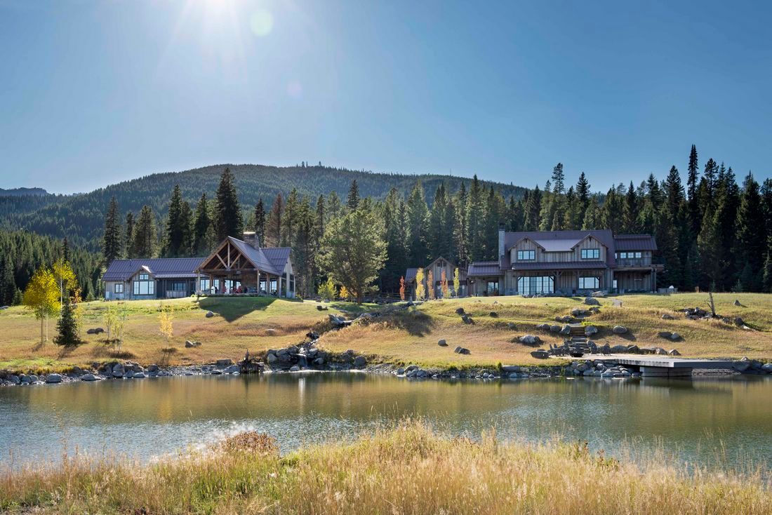 A large house is sitting on top of a hill next to a lake.
