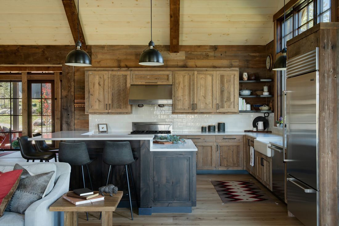 A kitchen with wooden cabinets and stainless steel appliances in a log cabin.