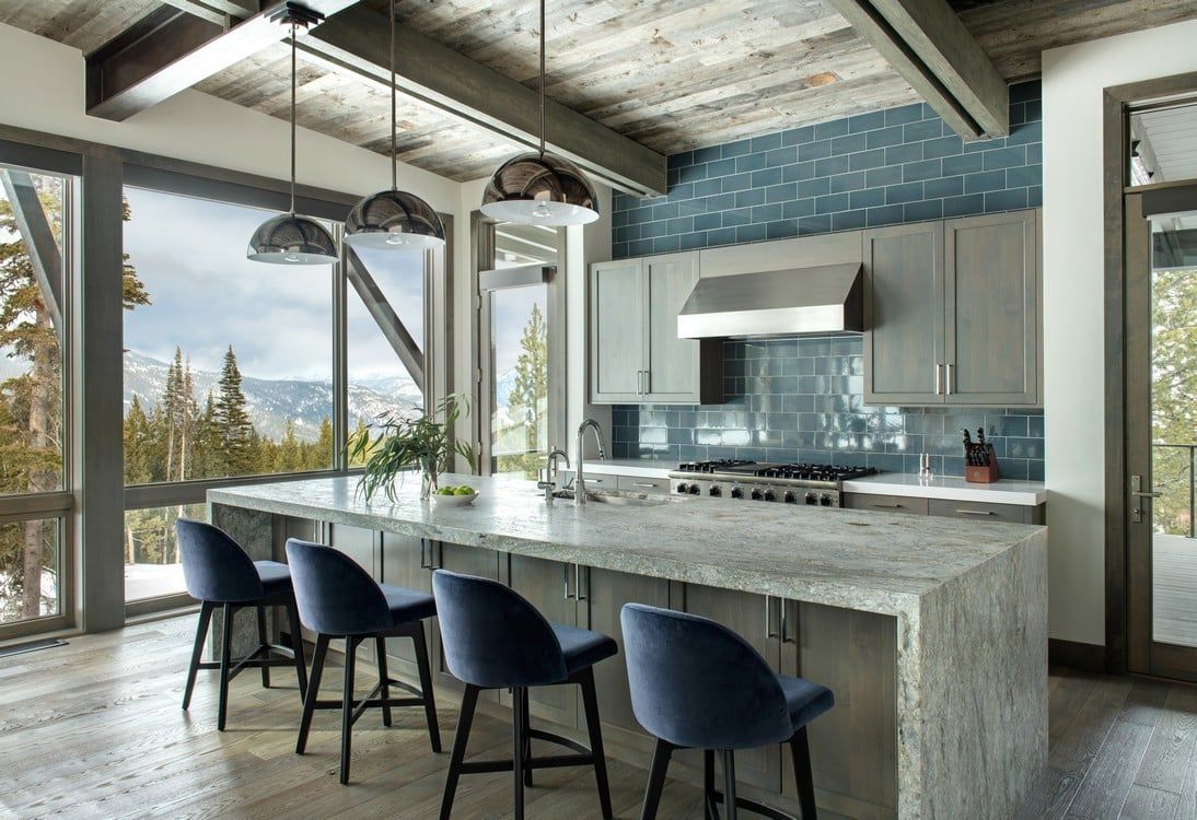 A kitchen with a large island and blue chairs.