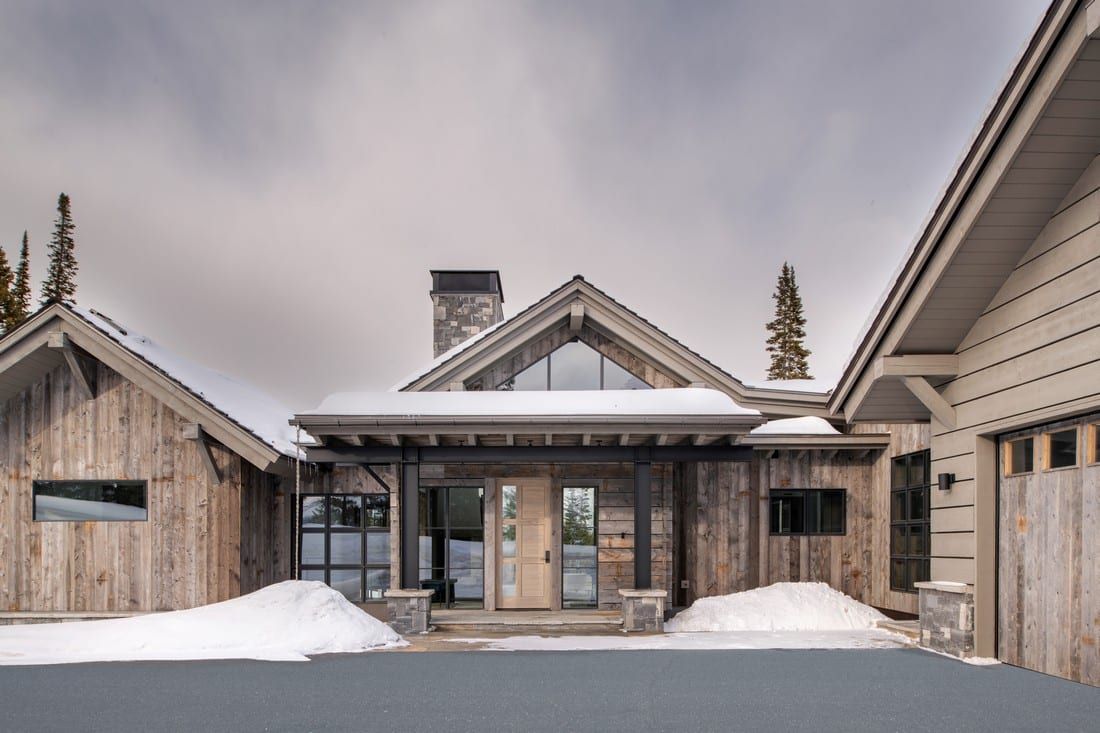 A large wooden house with snow on the ground in front of it