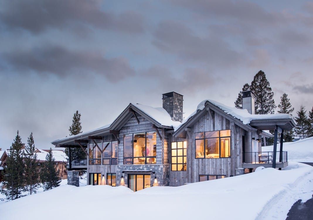 A large house is sitting on top of a snow covered hill.