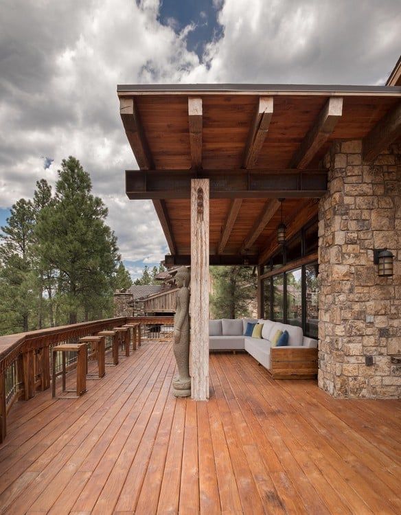 A wooden deck with a couch and stools on it