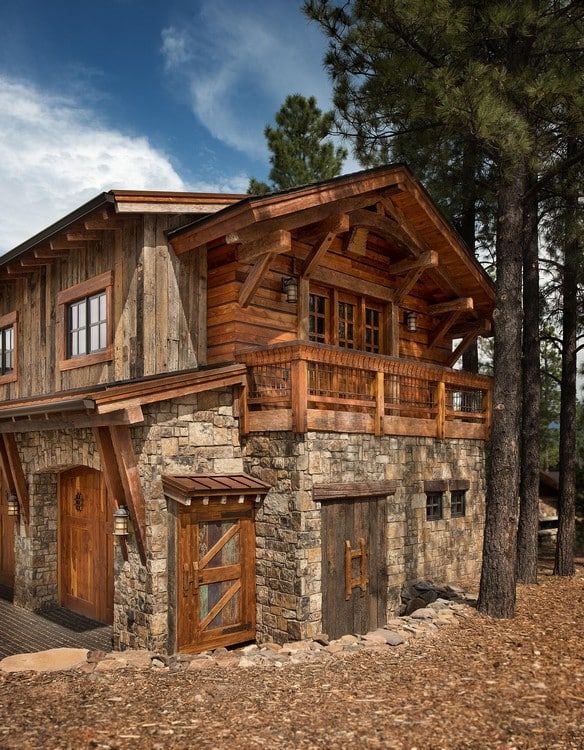 A large wooden and stone house is surrounded by trees.