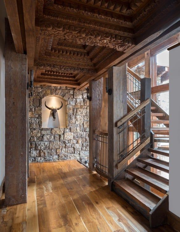 A hallway with a wooden staircase and a stone wall.