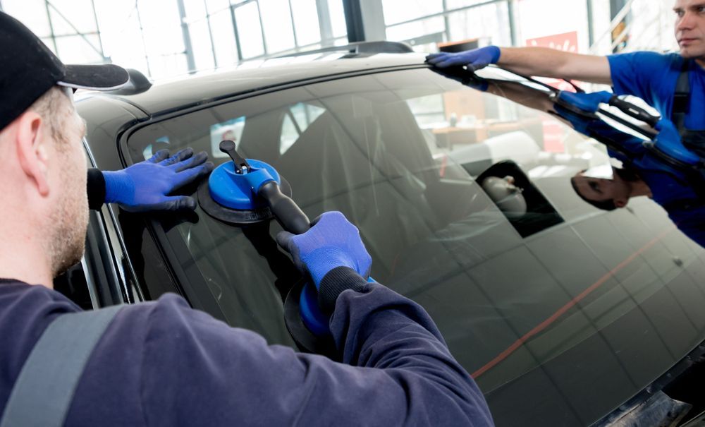 A Man Is Installing A Windshield On A Car — Eurobodalla Windscreens in Narooma, NSW