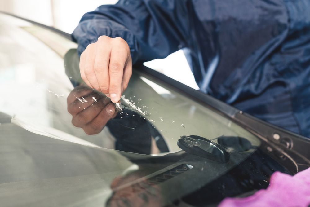 Hands Cleaning a Car Windshield with A Cloth in A Garage — Eurobodalla Windscreens in Bodalla, NSW