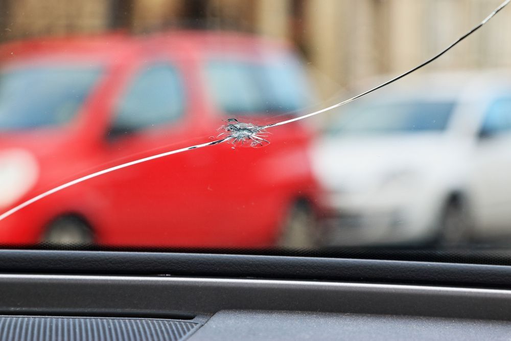 A Close Up Of A Broken Windshield In A Car With A Red Car In The Background — Eurobodalla Windscreens in Batemans Bay, NSW