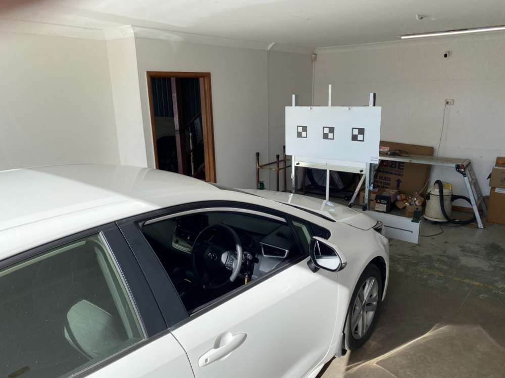 A White Car Is Parked In A Garage Next To A White Board With Squares On It — Eurobodalla Windscreens in Moruya, NSW