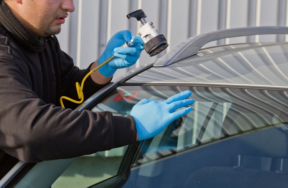 Person Using a Spray Gun to Coat a Car Windshield with Blue Tinted Paint or Film — Eurobodalla Windscreens in Dalmeny, NSW