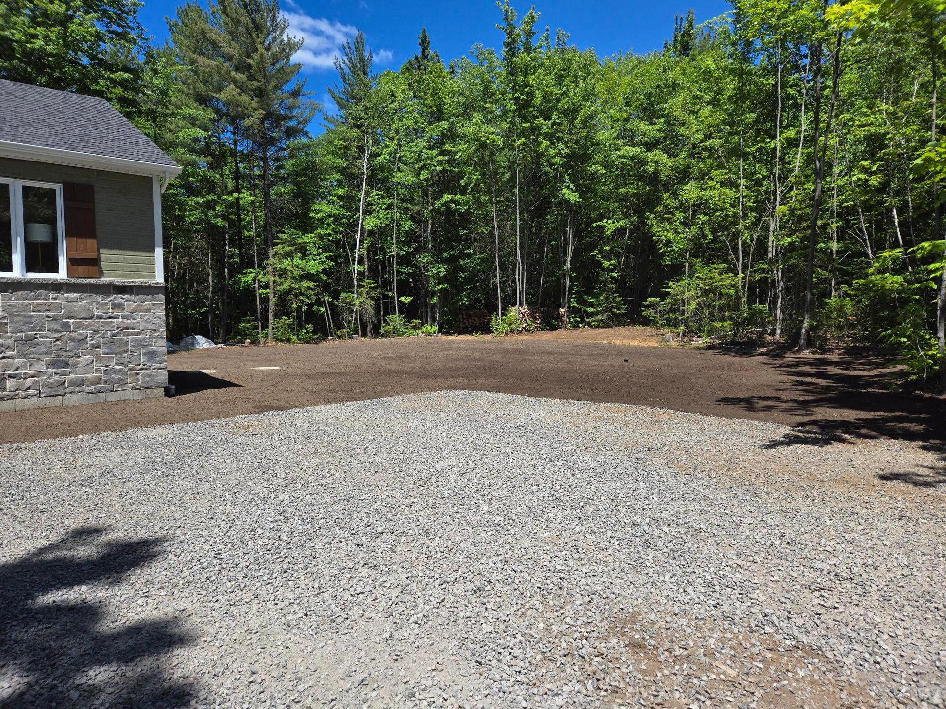 Une allée de gravier menant à une maison dans les bois