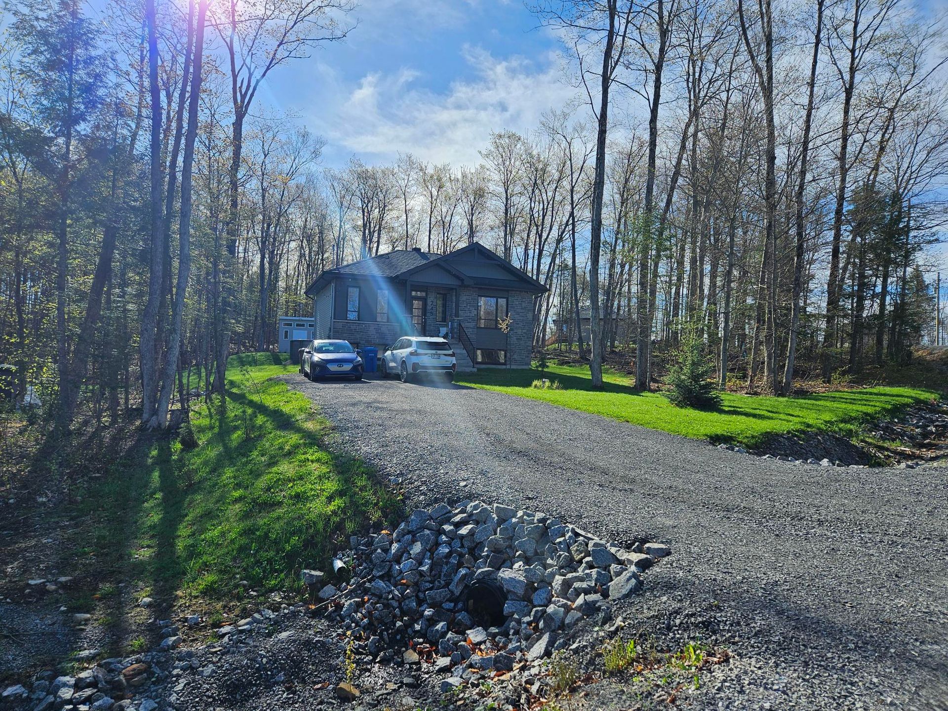 Une maison est entourée d'arbres et d'une allée de gravier.