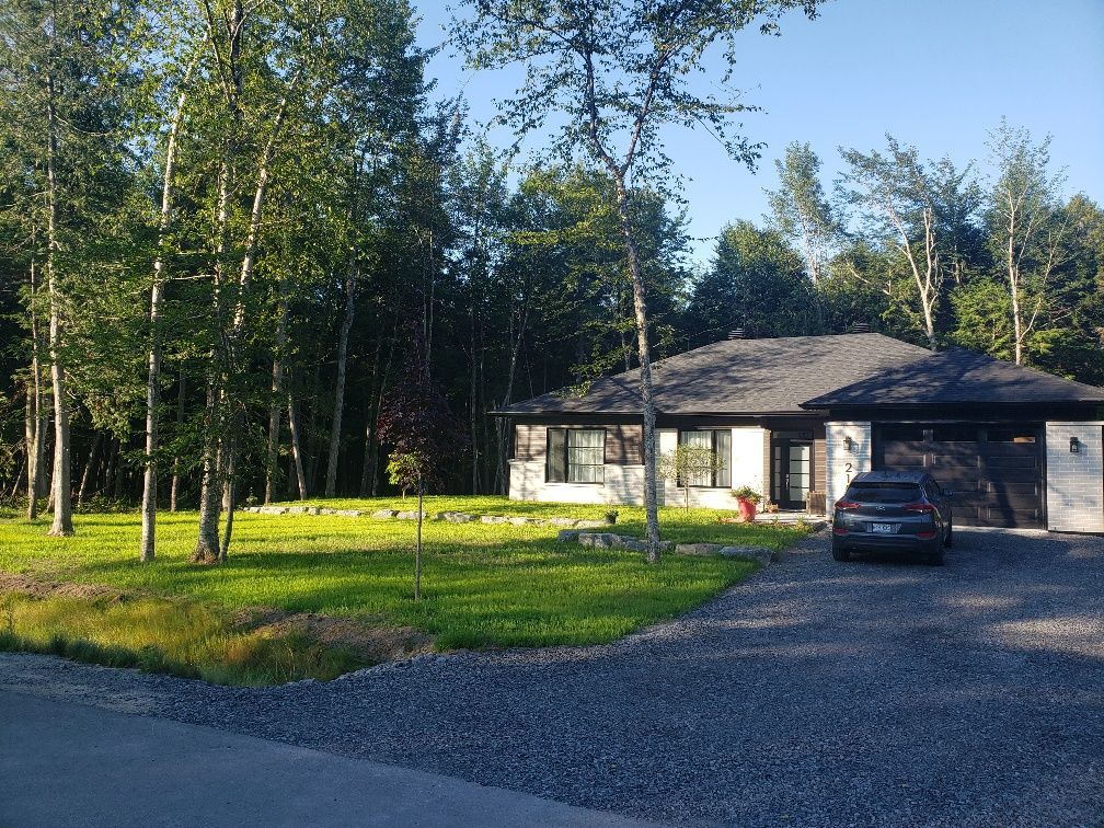 Une maison avec une voiture garée devant entourée d'arbres.