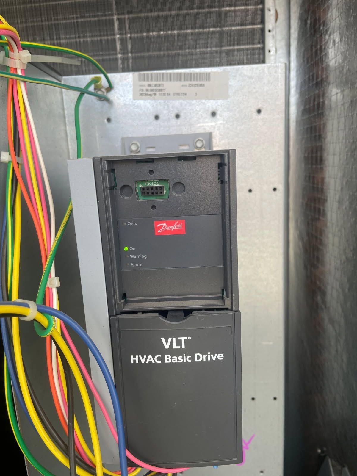 Wall-mounted Danfoss VLT HVAC drive with multicolored wires inside a metal electrical cabinet