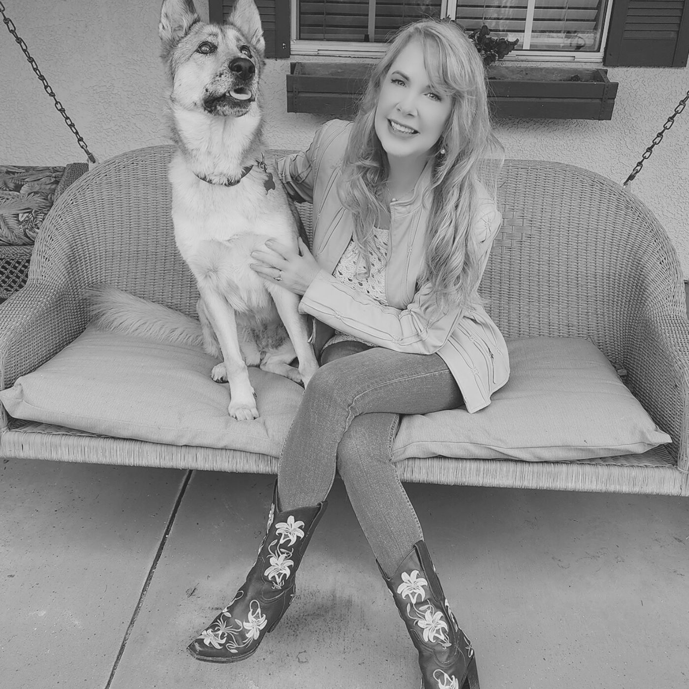 A woman is sitting on a porch swing holding a dog