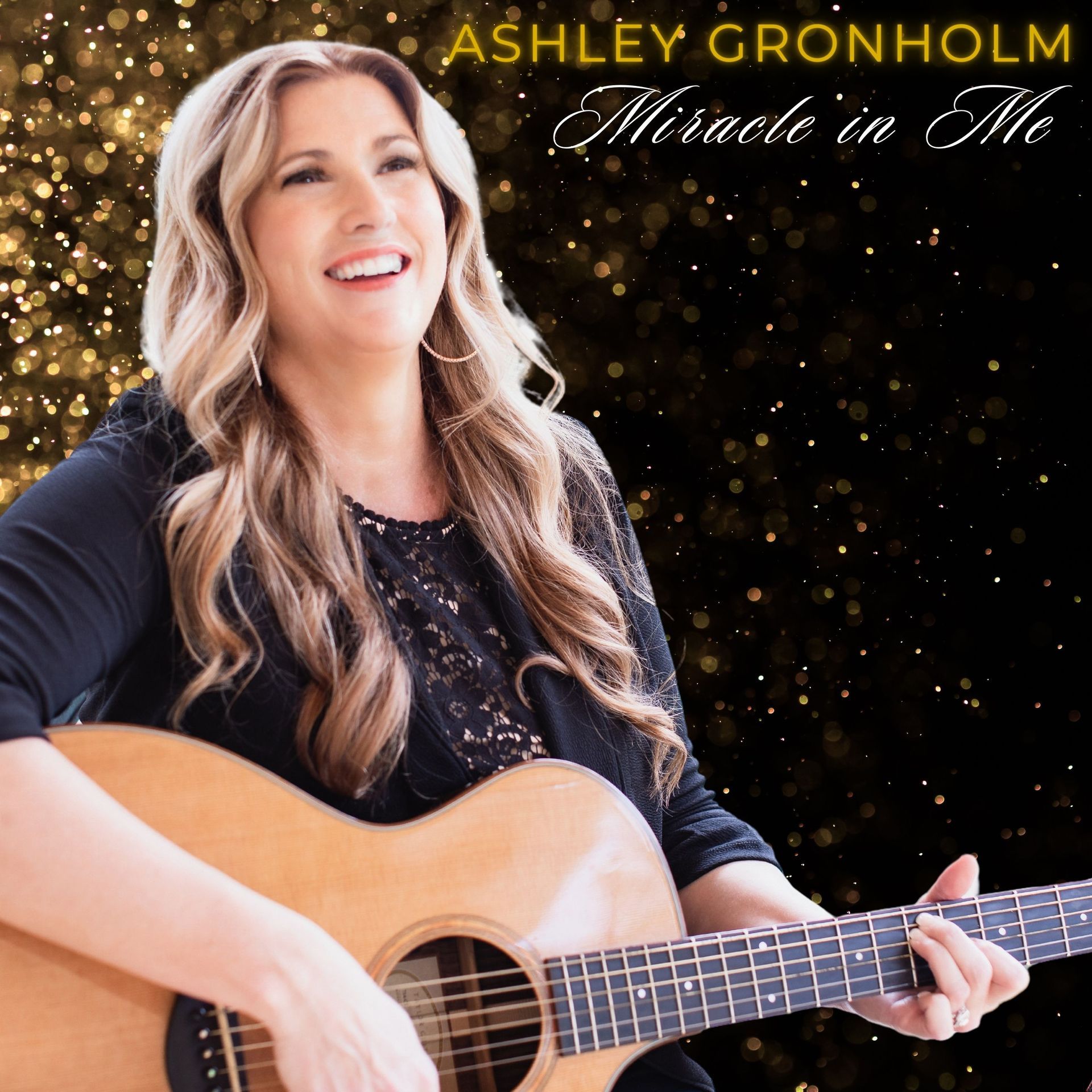 Ashley gronholm is smiling while holding a guitar