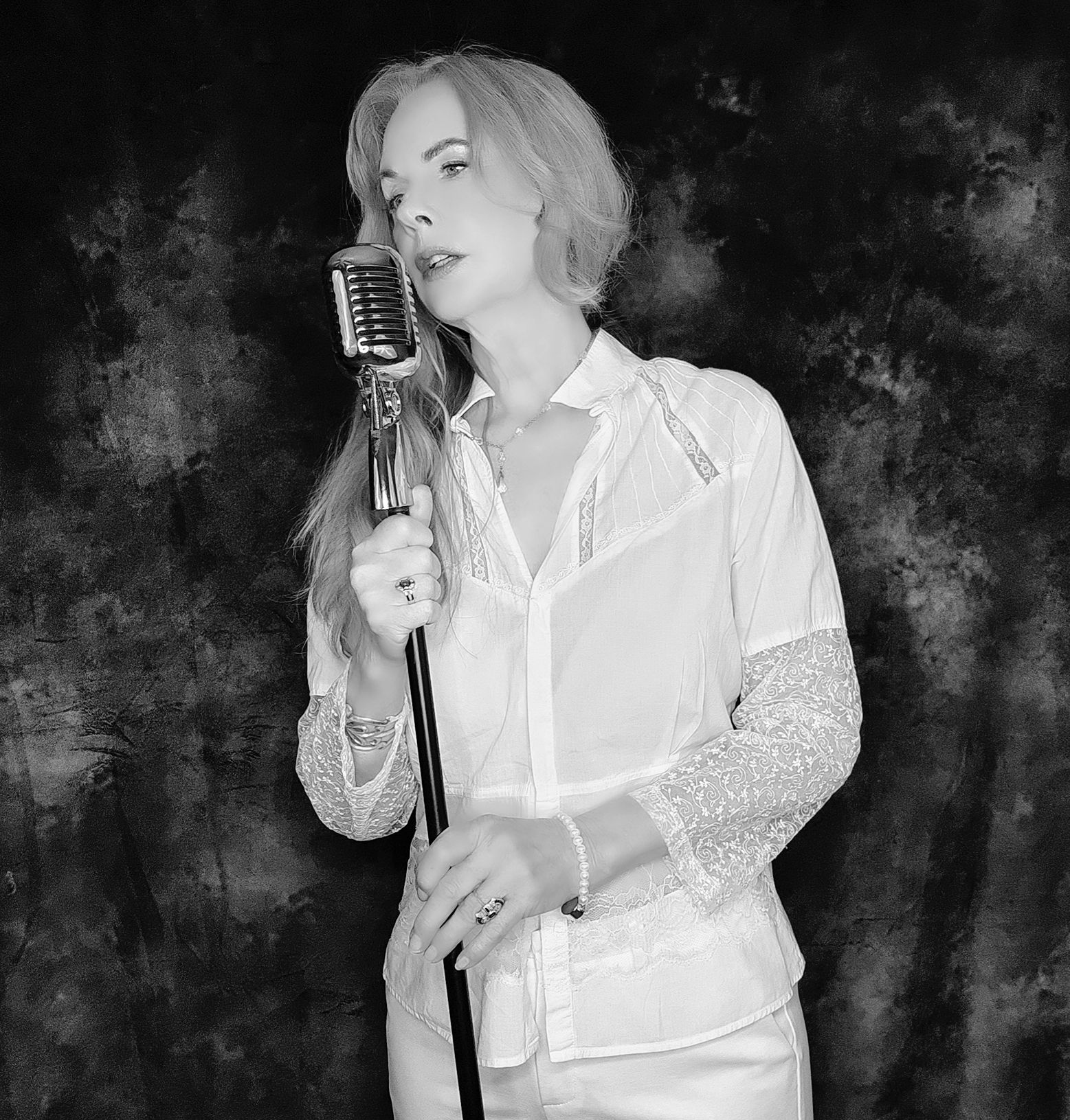 A woman in a white shirt is singing into a microphone