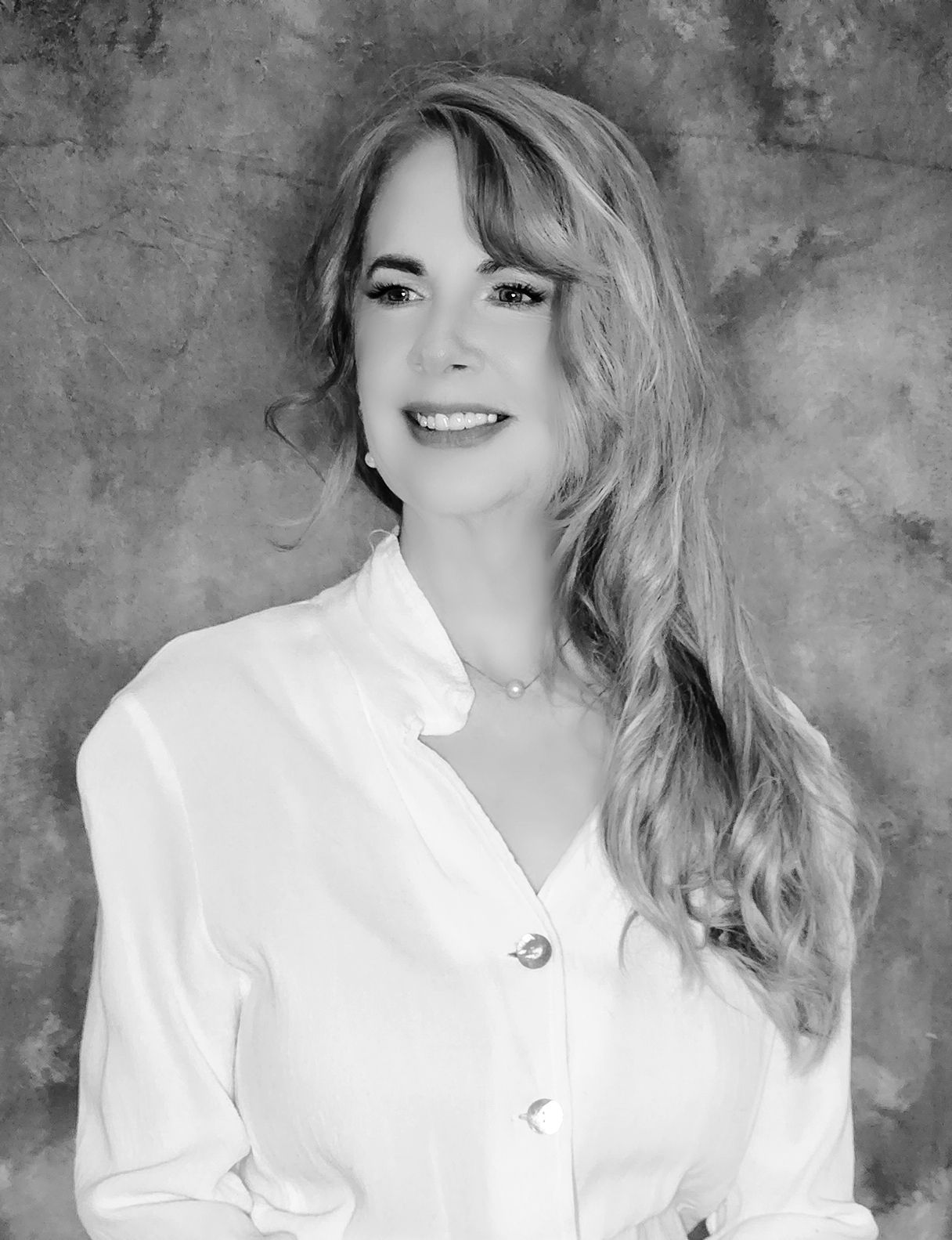 A woman in a white shirt is smiling in a black and white photo.