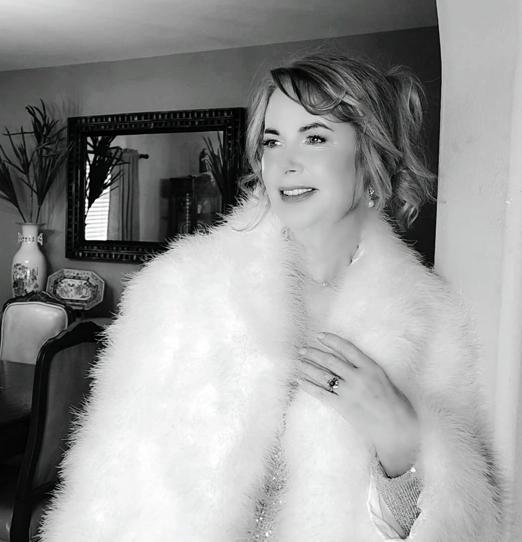 A woman is wearing a white fur coat in a black and white photo.