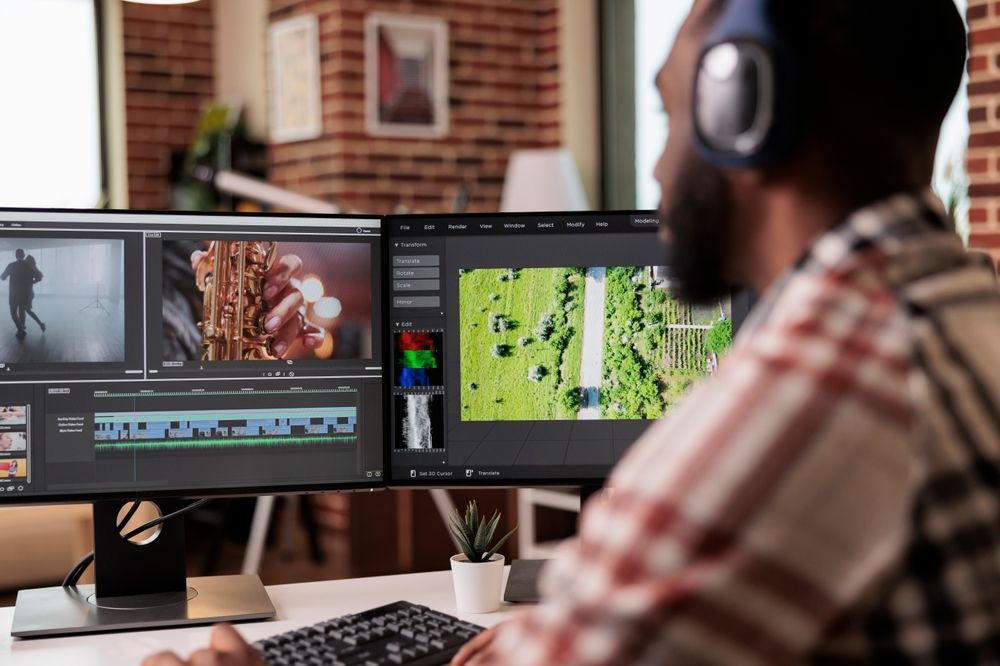 A man wearing headphones is sitting in front of two computer monitors.