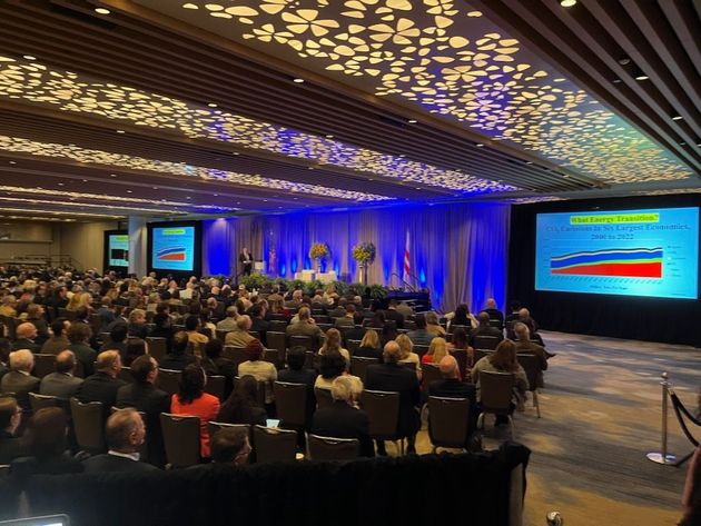 A large group of people are sitting in a conference room watching a presentation