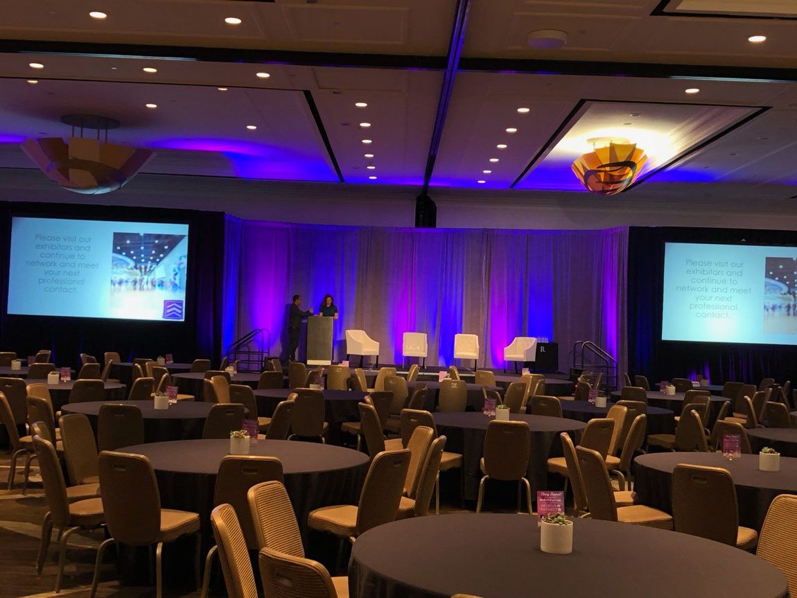 A large room filled with tables and chairs and a podium.