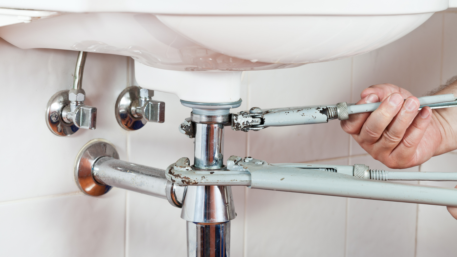 a person is fixing a sink with a wrench .
