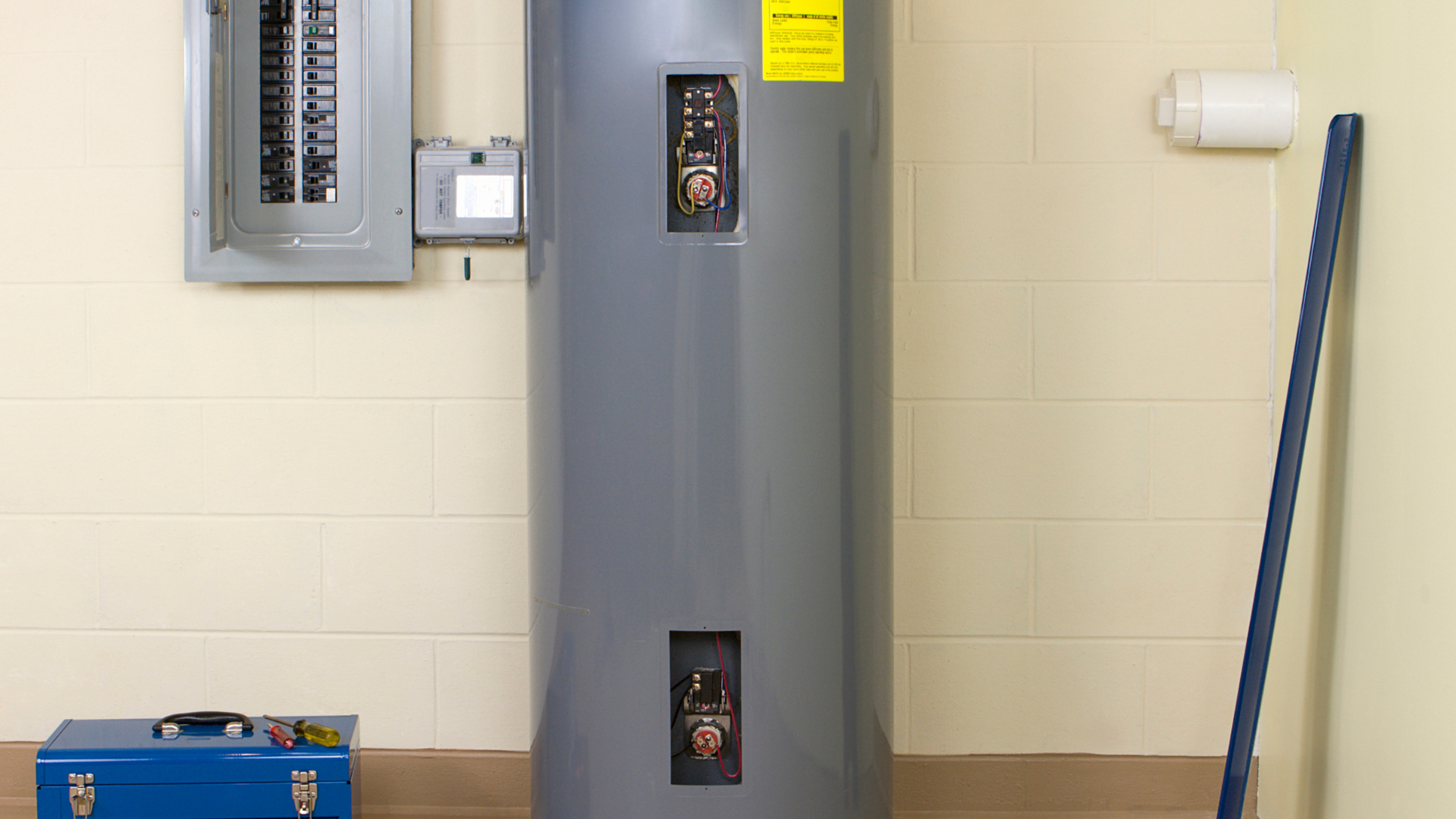 a water heater is sitting in a room next to a toolbox and a mop
