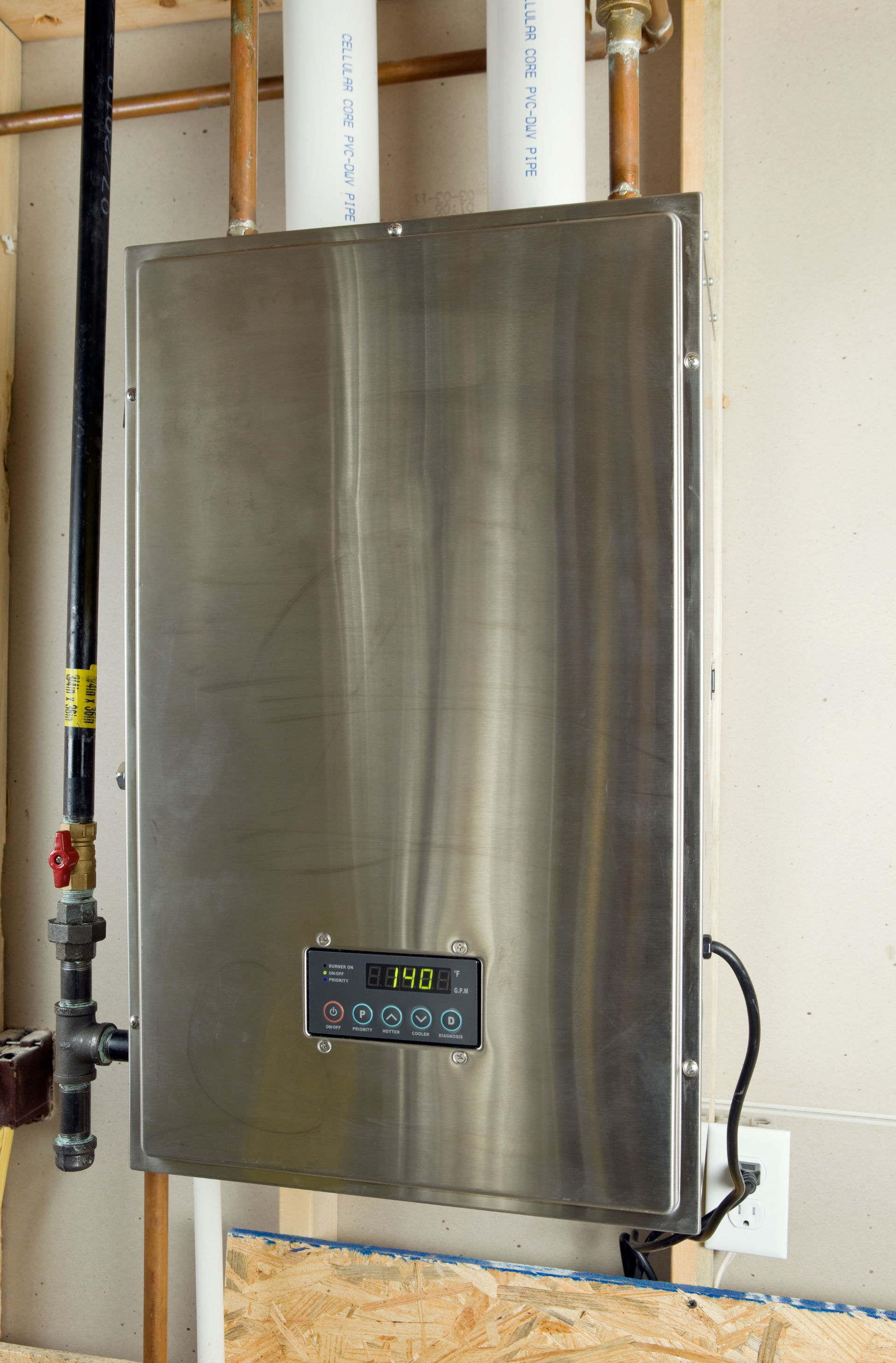 a stainless steel water heater is hanging on a wall next to pipes