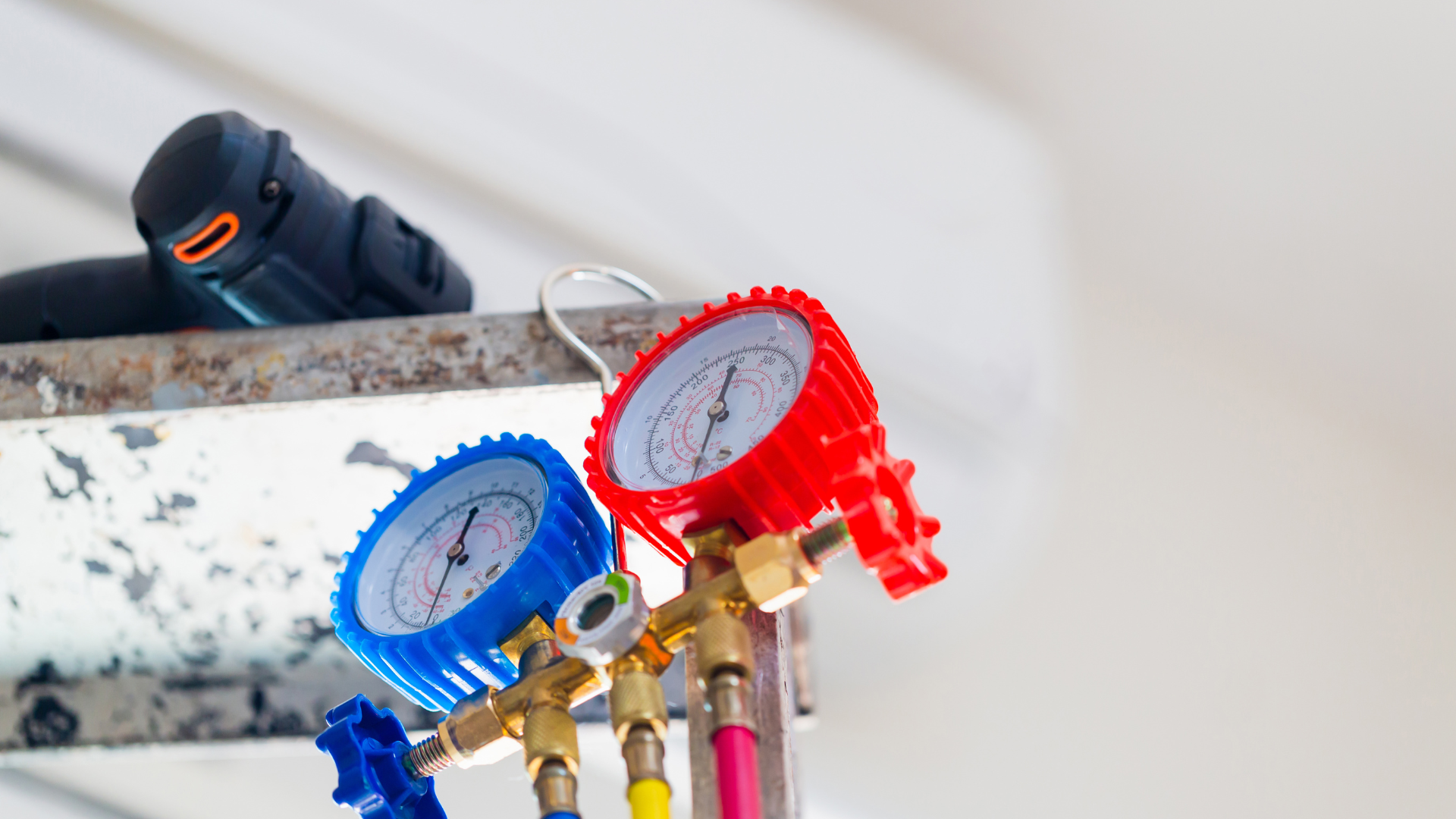 a couple of gauges hanging from the ceiling next to a drill for heater repair