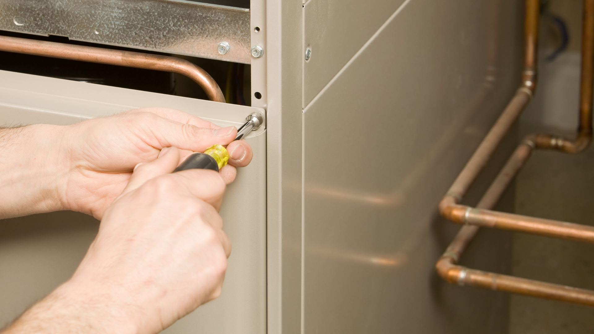 a person is working on a furnace with a screwdriver