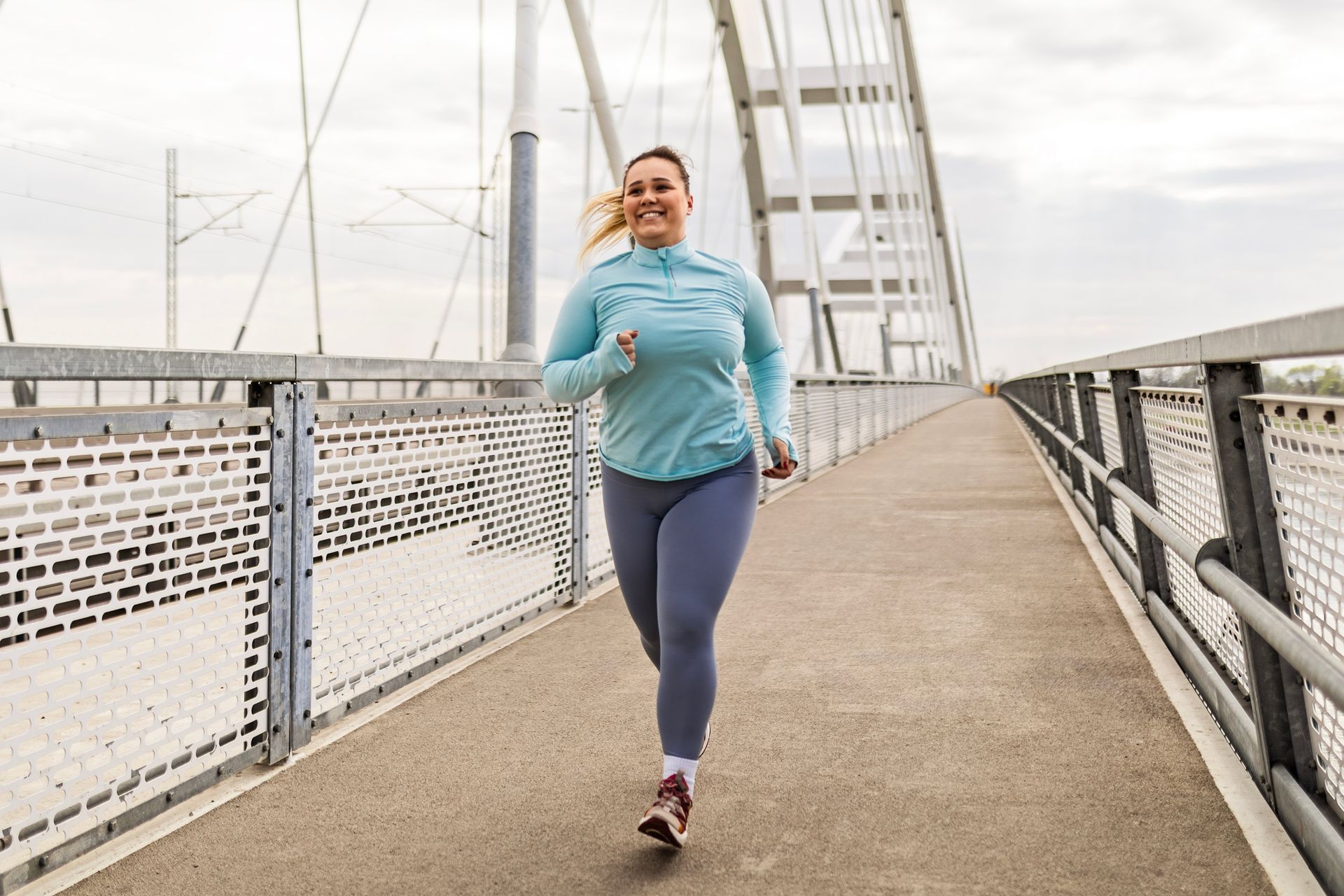 A woman is running on a bridge.
