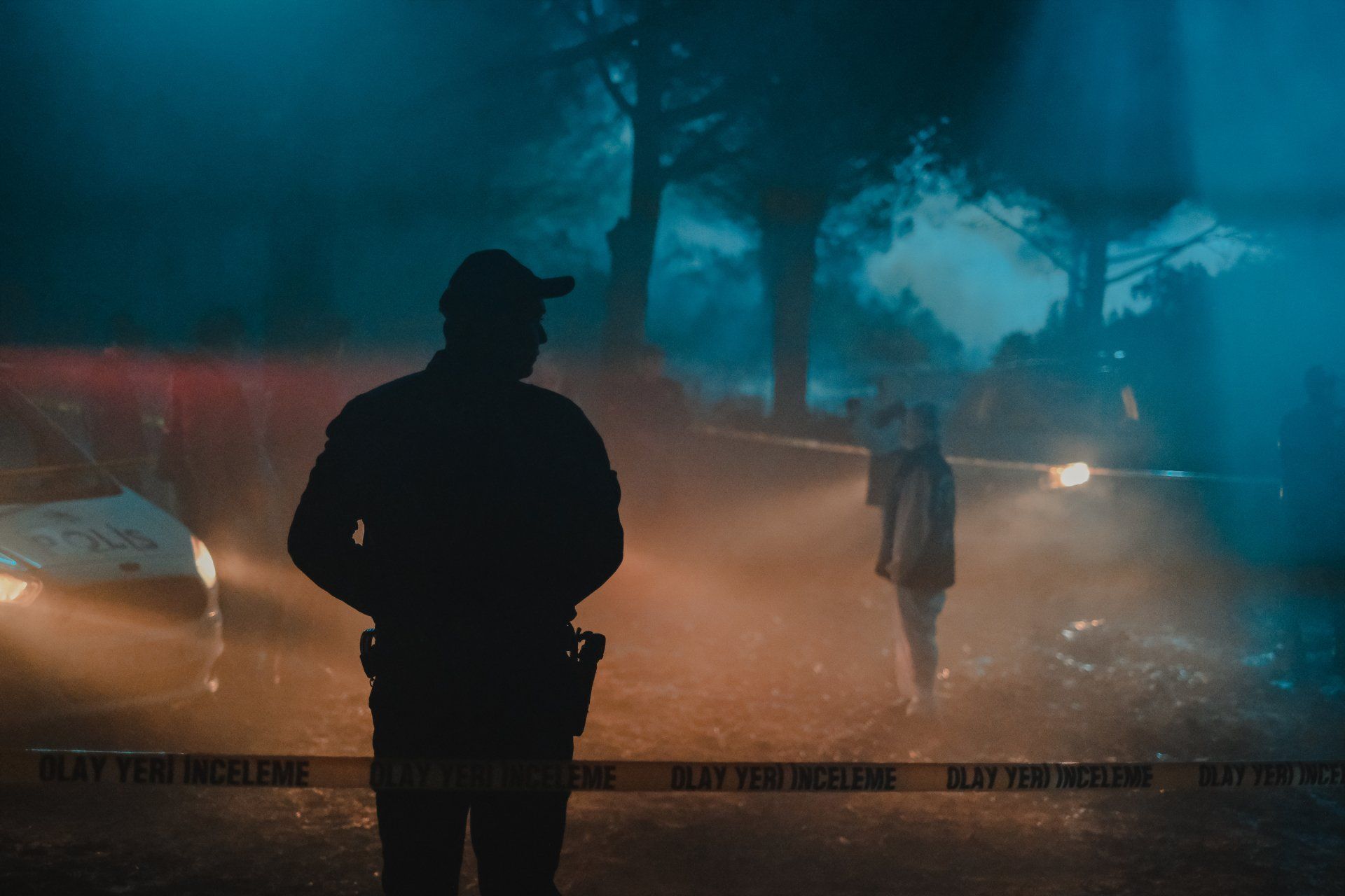 A police officer is standing next to a woman in a foggy forest.