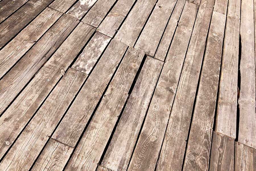 Weathered wooden deck planks laid diagonally in a rustic outdoor surface