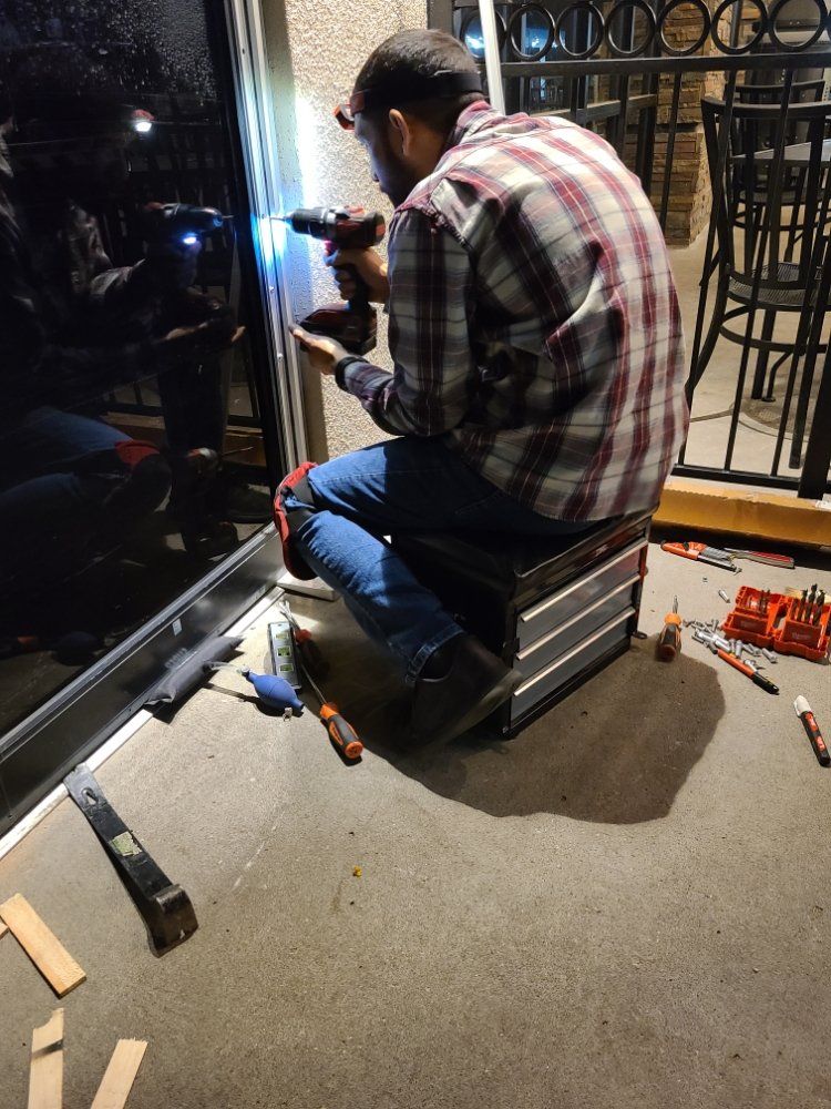 Locks Keys and More | A man is kneeling down using a drill to fix a door.