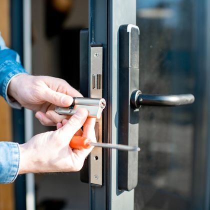Locks Keys and More | A person is fixing a door lock with a screwdriver.