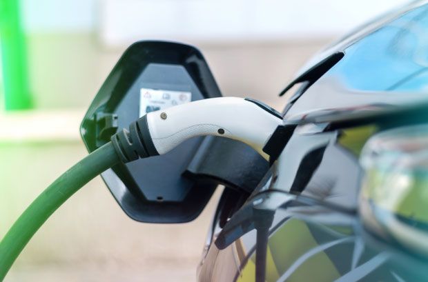Electric car charging with a green charging cable connected to the car.