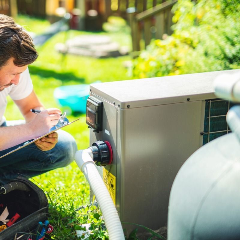 Man inspecting pool equipment, writing on clipboard outdoors.
