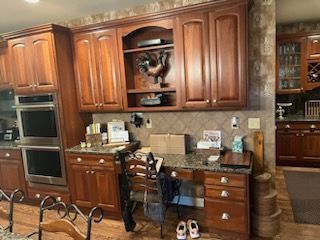 A kitchen with wooden cabinets , granite counter tops , and stainless steel appliances.