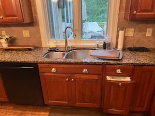 A kitchen with a sink , dishwasher , cabinets and a window.