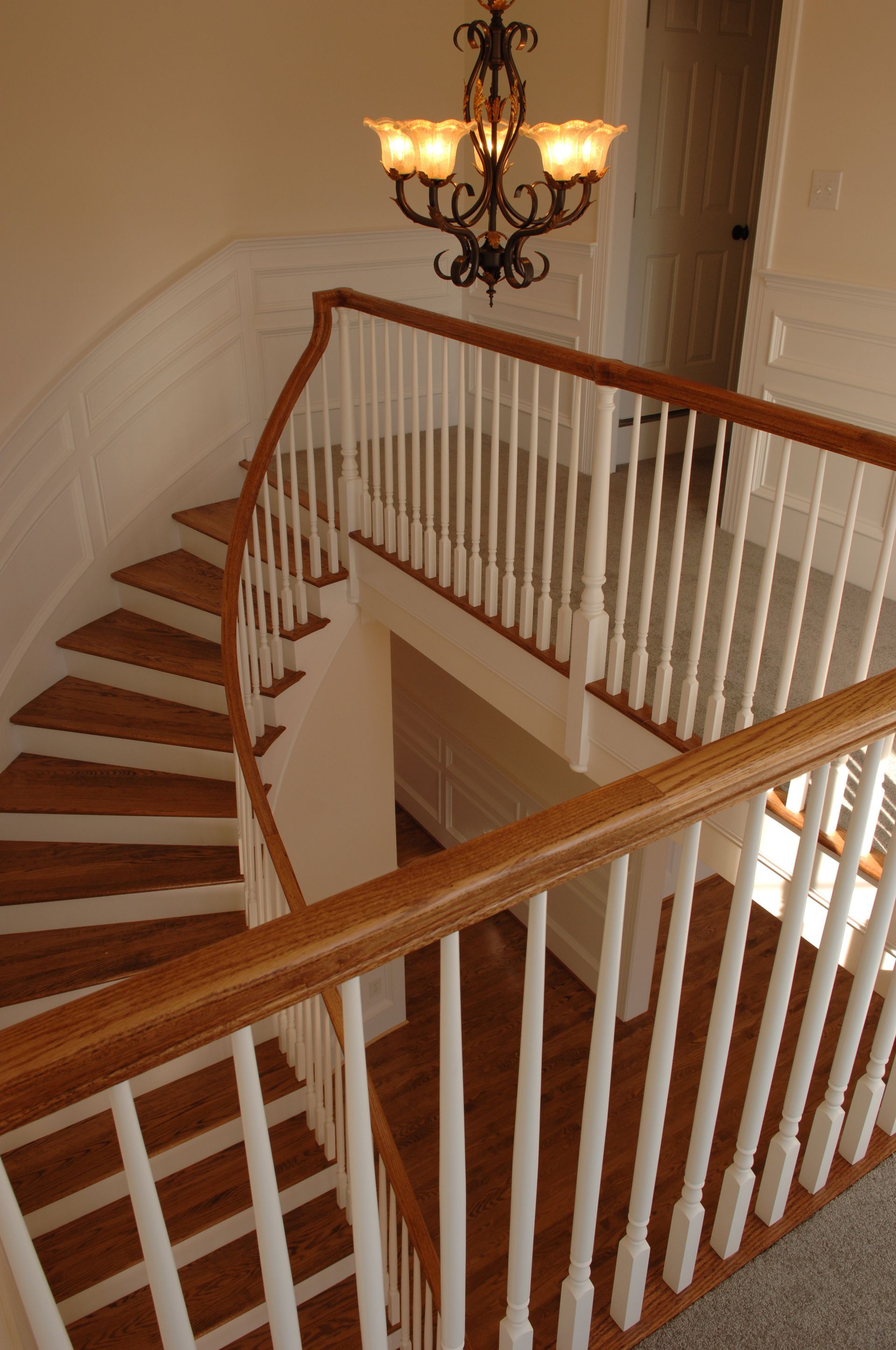 A spiral staircase with a white railing and a chandelier hanging from the ceiling