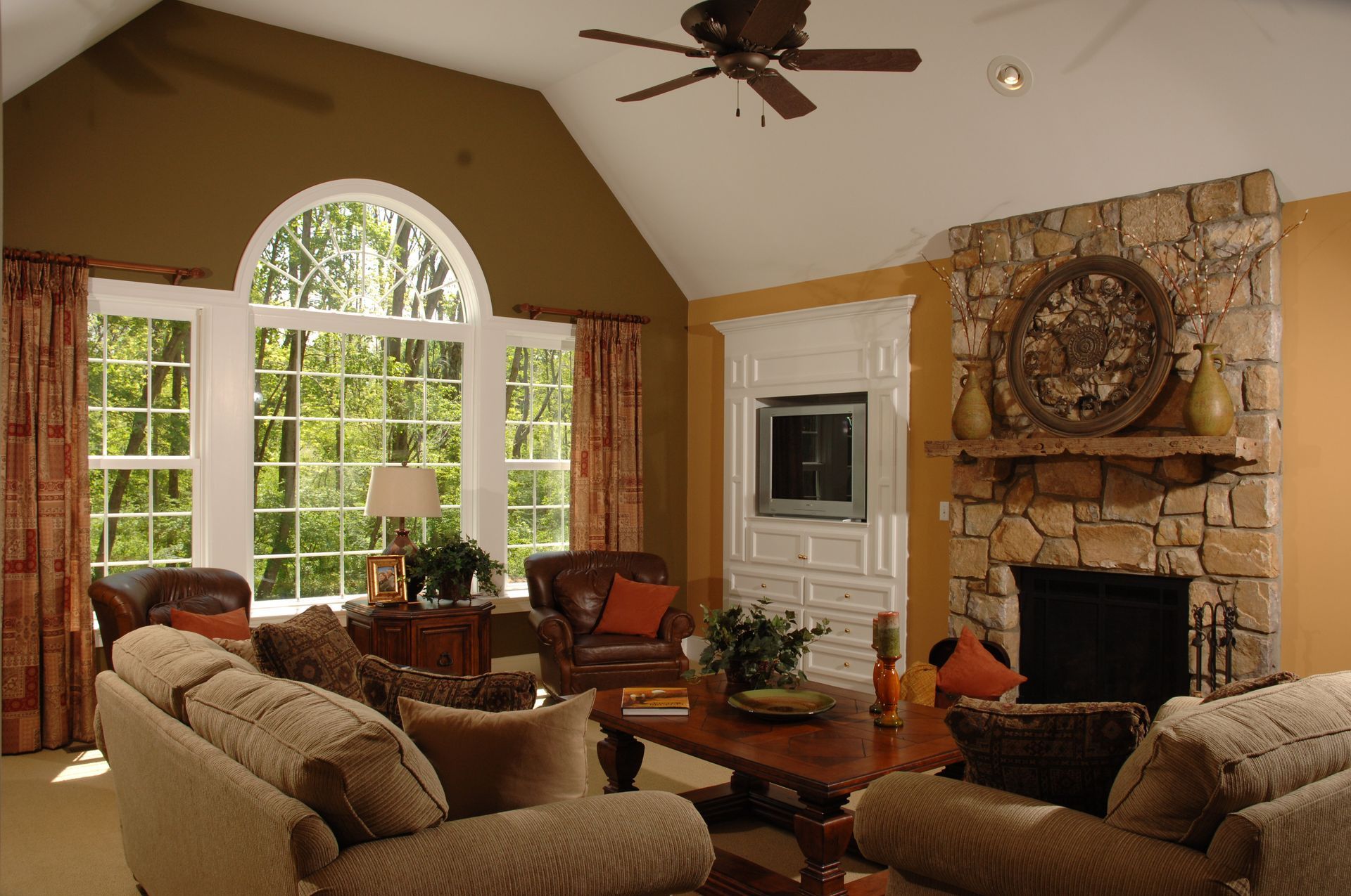 A living room with a fireplace and a ceiling fan