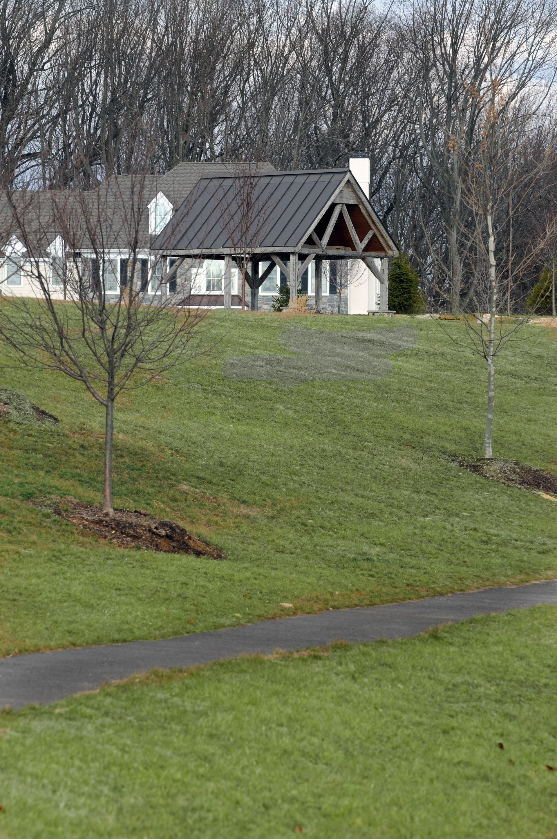 A house is sitting on top of a grassy hill next to a path.