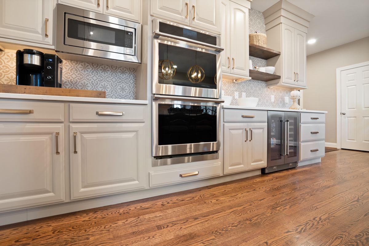 A kitchen with white cabinets , stainless steel appliances , and hardwood floors.