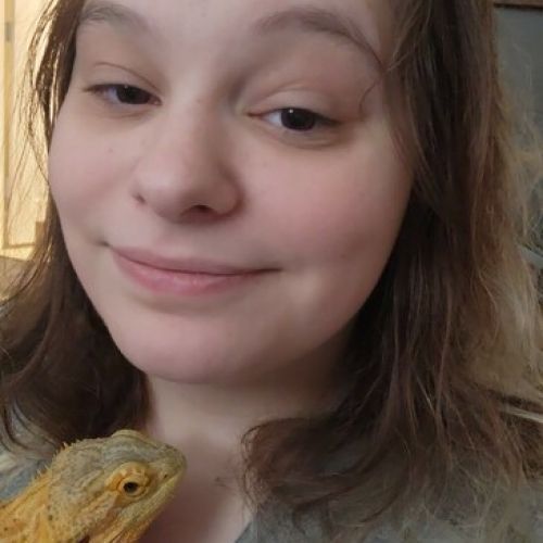 Woman smiling beside a yellow bearded dragon in a close-up selfie