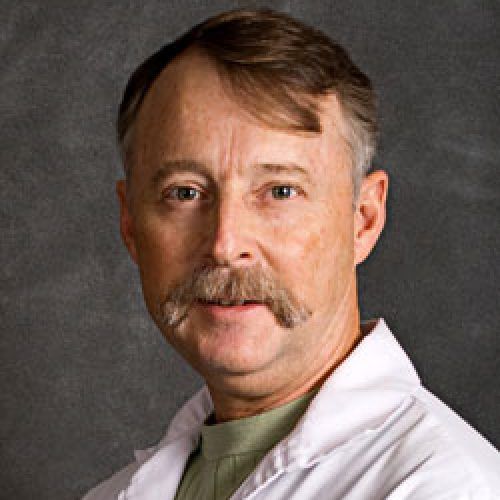 Portrait of a man in a white coat against a dark studio background