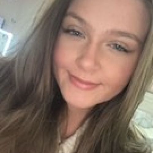 Close-up selfie of a smiling woman with long hair indoors