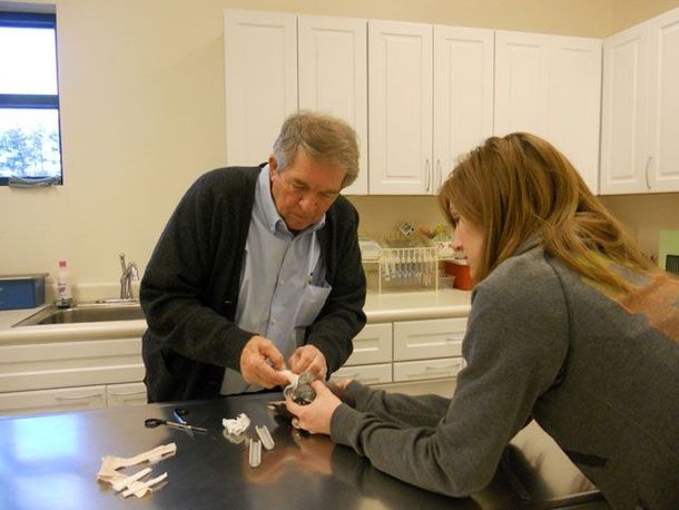 Two people working together at a kitchen counter, examining a small object.